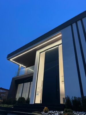 Porta pivotante em ACM preto fosco com portais duplos laterais em vidro.