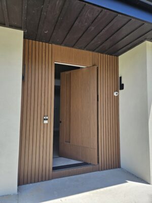 Porta pivotante em ACM Wood Nogueira com portais duplos laterais ripados, destacando elegância e contemporaneidade - Imagem 3