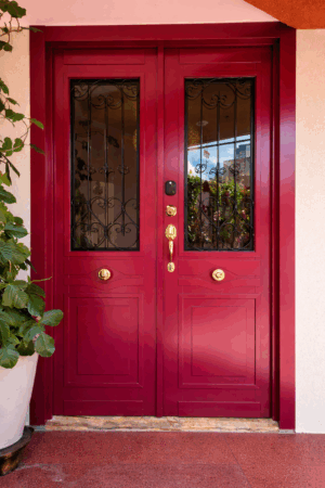 Porta em ACM com sistema de abertura dupla em estilo colonial, equipada com grade em ferro, aldrava decorativa, fechaduras blim blim e digital