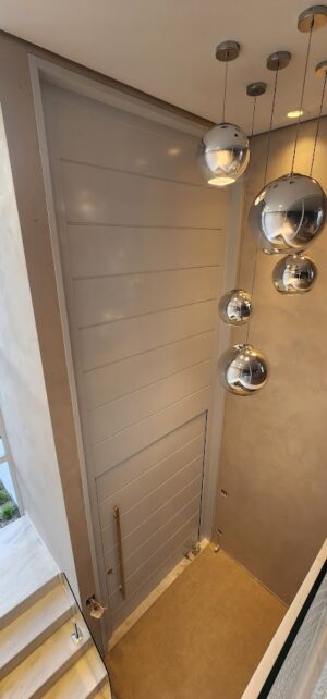 Porta pivotante em ACM com frisos horizontais e bandeira superior fixa. Modelo moderno, resistente e elegante, ideal para valorizar a fachada - Imagem 5