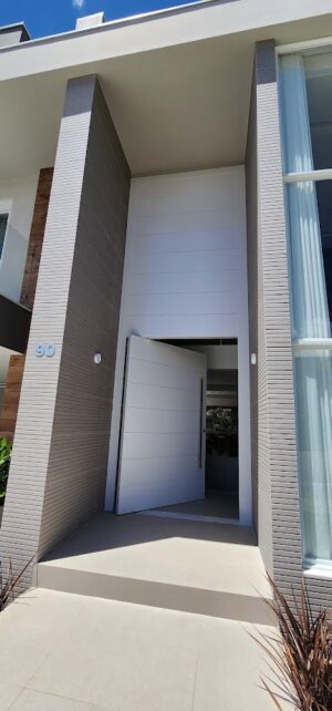 Porta pivotante em ACM com frisos horizontais e bandeira superior fixa. Modelo moderno, resistente e elegante, ideal para valorizar a fachada - Imagem 3