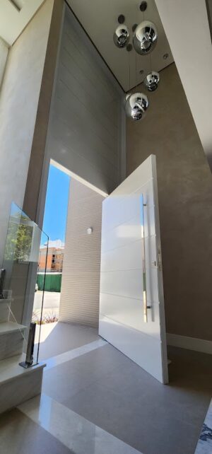 Porta pivotante em ACM com frisos horizontais e bandeira superior fixa. Modelo moderno, resistente e elegante, ideal para valorizar a fachada - Imagem 4