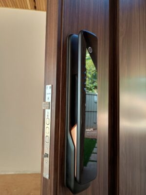 Porta pivotante em ACM com puxador cava, modelo ripado vertical e bandeira superior fixa, destacando design moderno e elegante - Imagem 3