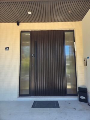 Porta em ACM modelo ondulado, com portais laterais em vidro, acabamento externo wood sucupira e interno champanhe, unindo duas faces com estilos distintos