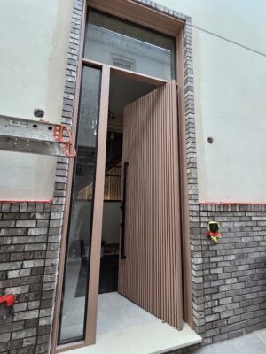 Porta pivotante em ACM modelo ripado, com portal e bandeira em vidro, destacando leveza e sofisticação no projeto - Imagem 2