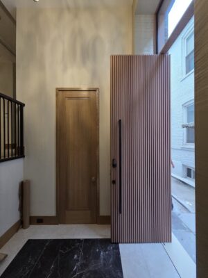 Porta pivotante em ACM modelo ripado, com portal e bandeira em vidro, destacando leveza e sofisticação no projeto - Imagem 3