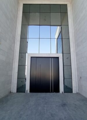 Porta pivotante em ACM com frisos verticais decorativos